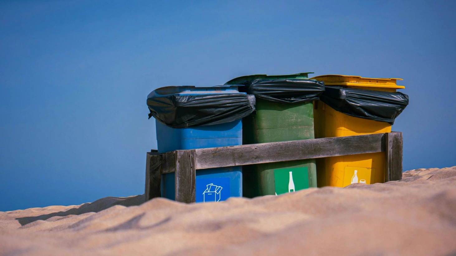 Poubelles de tri sélectif colorées sur une plage pour illustrer la gestion responsable des déchets et la protection de l'environnement, un pilier clé de la RSE dans le nettoyage.