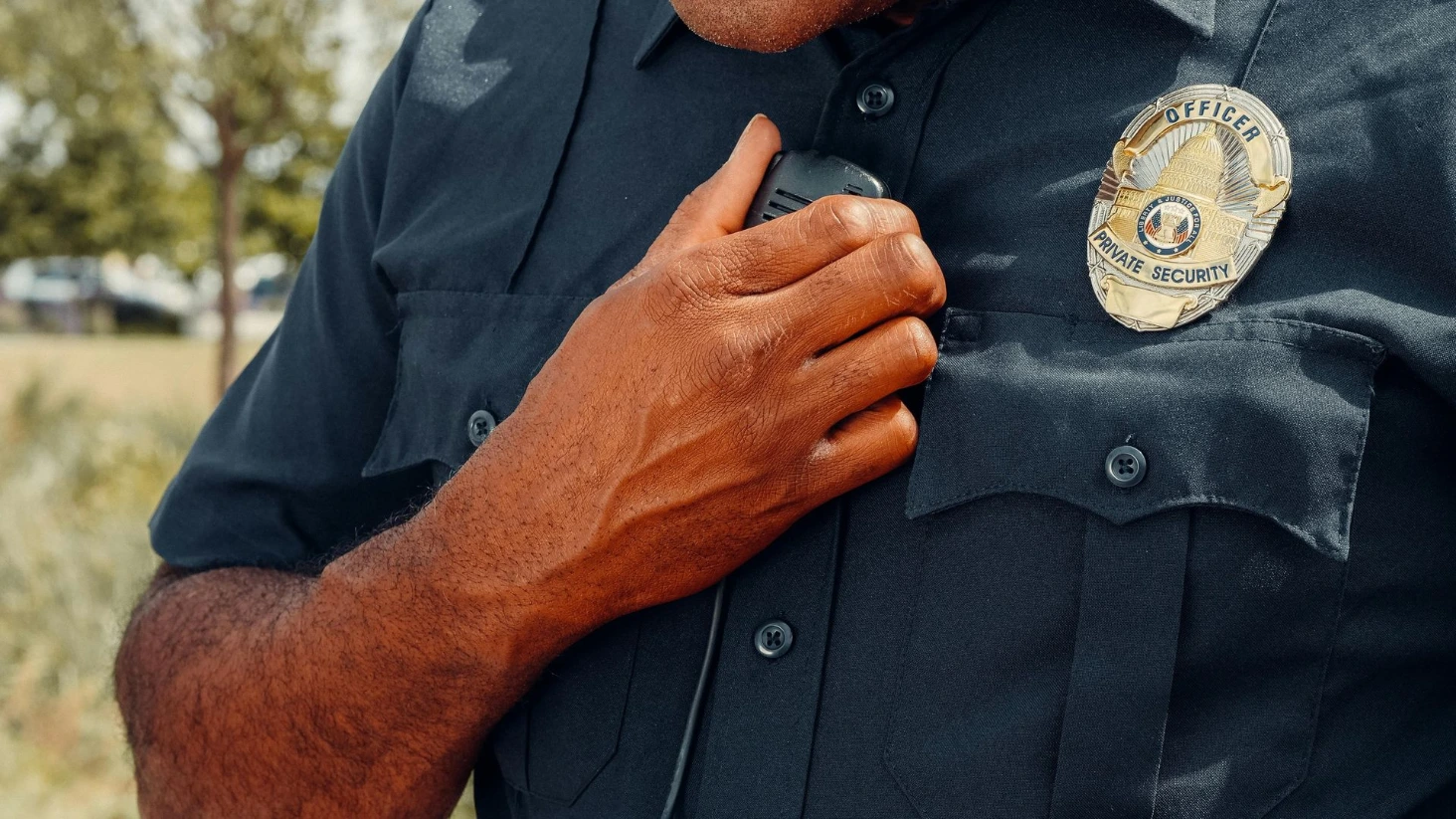 Agent de sécurité privée en uniforme utilisant une radio, illustrant le pilier social et la communication sur le terrain.