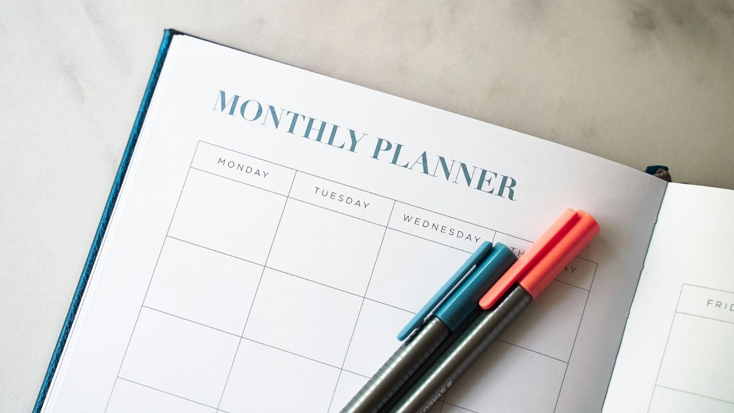 Agenda ouvert avec feutres posés dessus