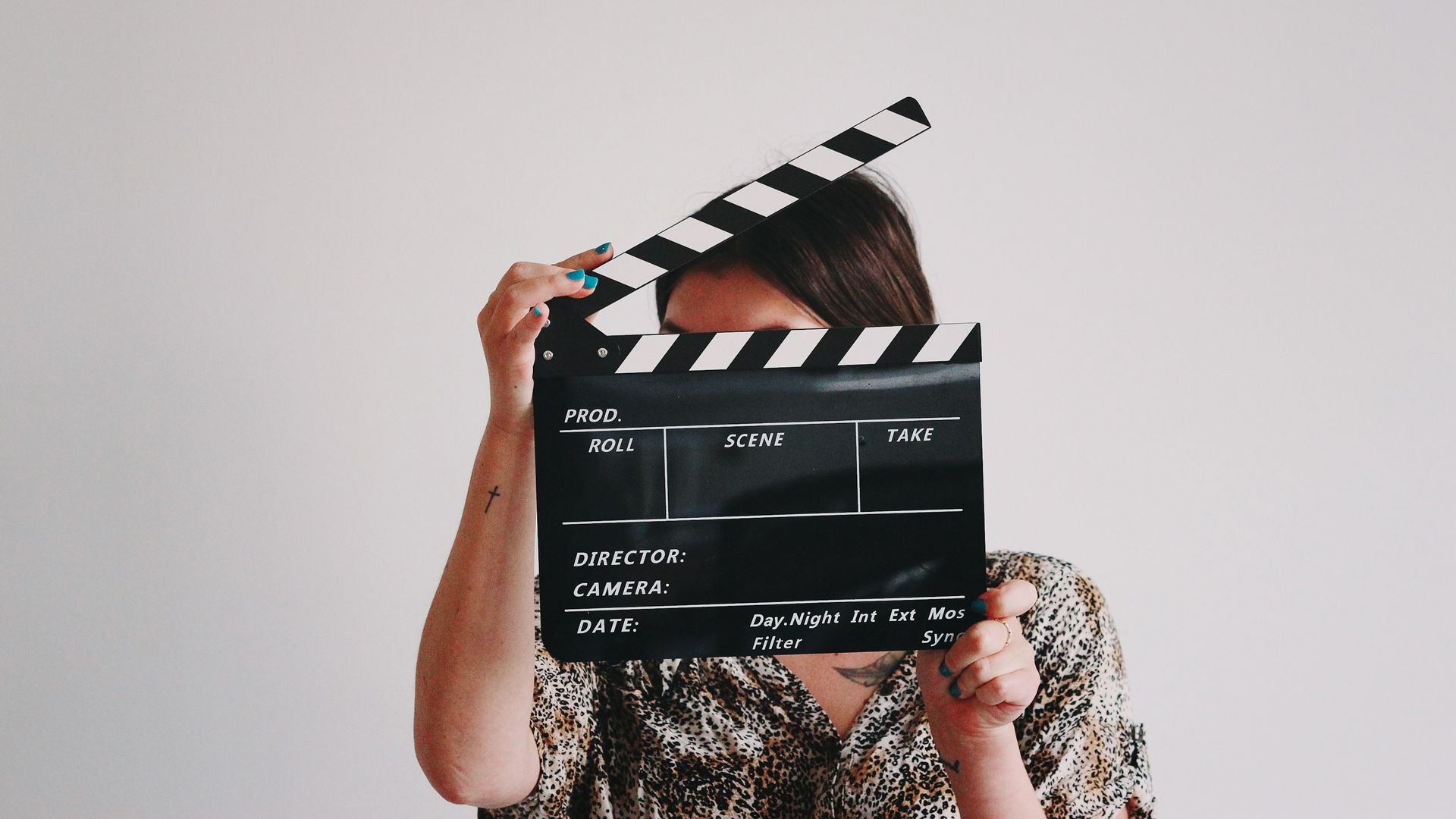 femme tenant un clap de cinéma devant son visage