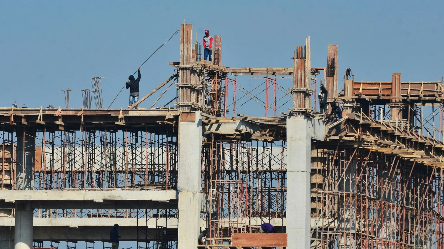"Ouvriers du bâtiment travaillant en hauteur sur le chantier de construction en béton d'un grand immeuble